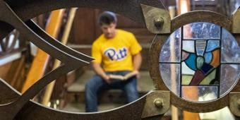 Student by a stained glass window in the Cathedral of Learning